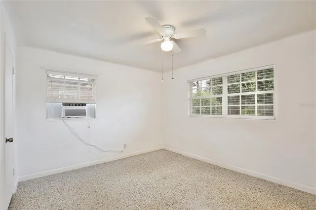 an empty room with windows and fan