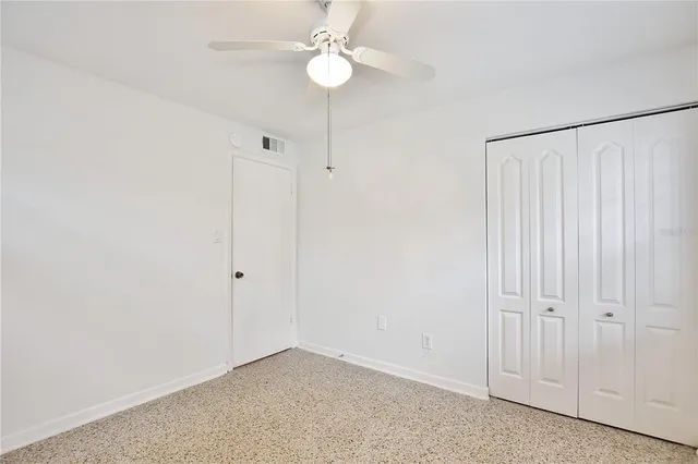 an empty room with a fan & a ceiling fan