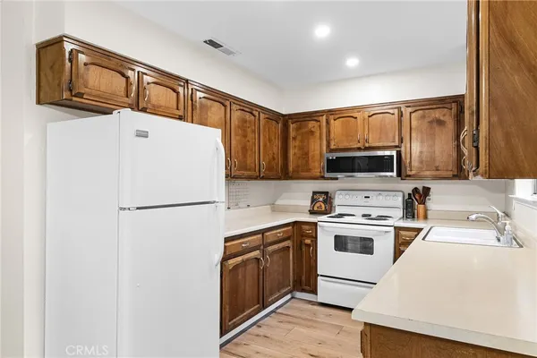 a white refrigerator freezer sitting inside of a kitchen with stainless steel appliances granite countertop white cabinets and wooden floor