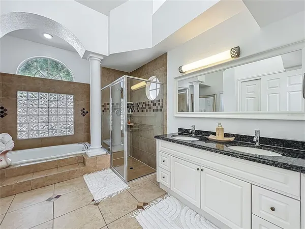 a spacious bathroom with a granite countertop sink a mirror a bathtub and next to a window