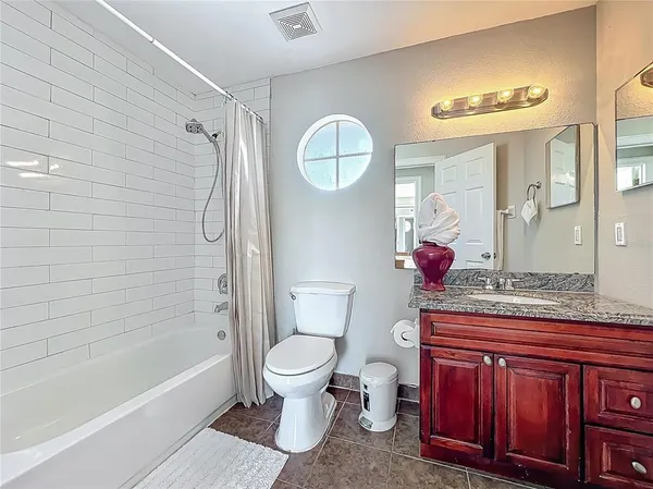 a bathroom with a granite countertop sink toilet mirror and bathtub