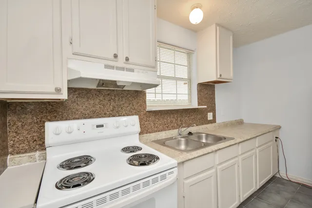 a kitchen with granite countertop white cabinets and white appliances