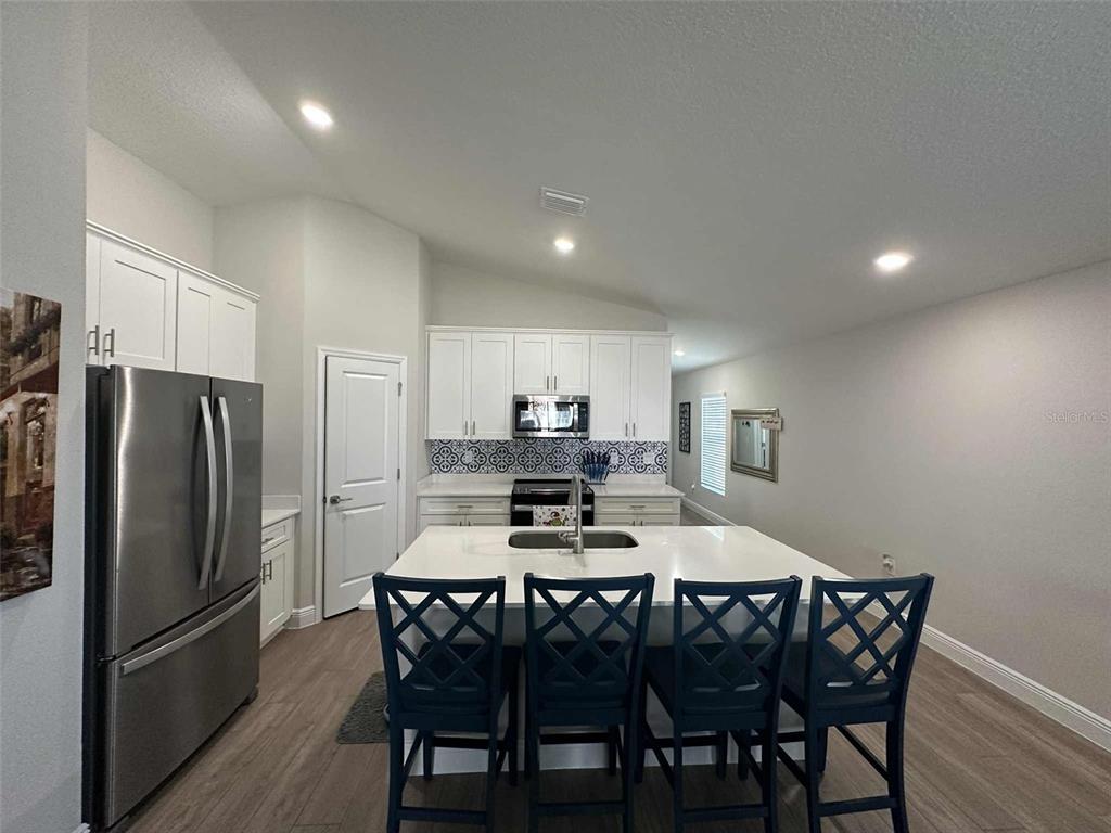 6245 Southwest 96th Place Ocala, FL 34476 - Photo 12 of 38 a kitchen with a dining table chairs refrigerator and cabinets