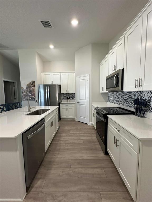 6245 Southwest 96th Place Ocala, FL 34476 - Photo 9 of 38 a large kitchen with stainless steel appliances granite countertop a stove top oven a sink dishwasher and a refrigerator with wooden floor