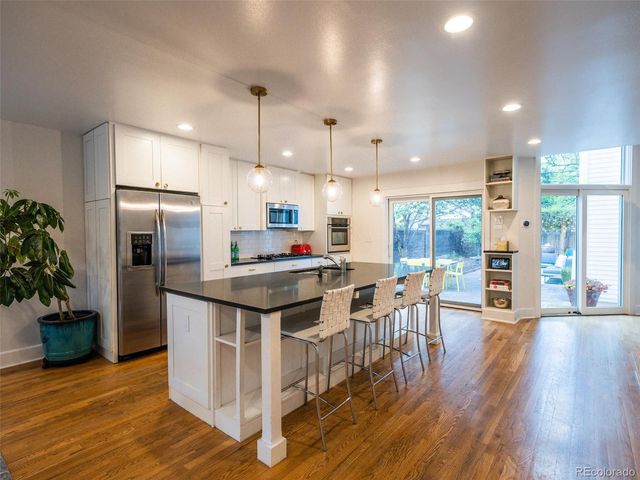 a kitchen with stainless steel appliances granite countertop a table chairs refrigerator and sink