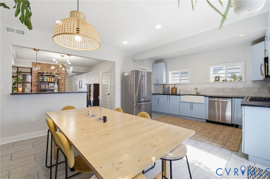 1602 Decatur Street Richmond, VA 23224 - Photo 4 of 25 a kitchen with stainless steel appliances kitchen island granite countertop a kitchen island a stove a sink a dining table and chairs