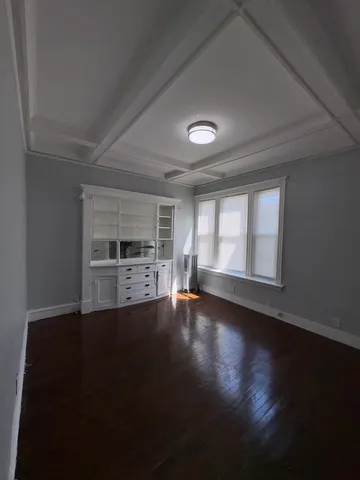 a view of a livingroom with wooden floor and a kitchen