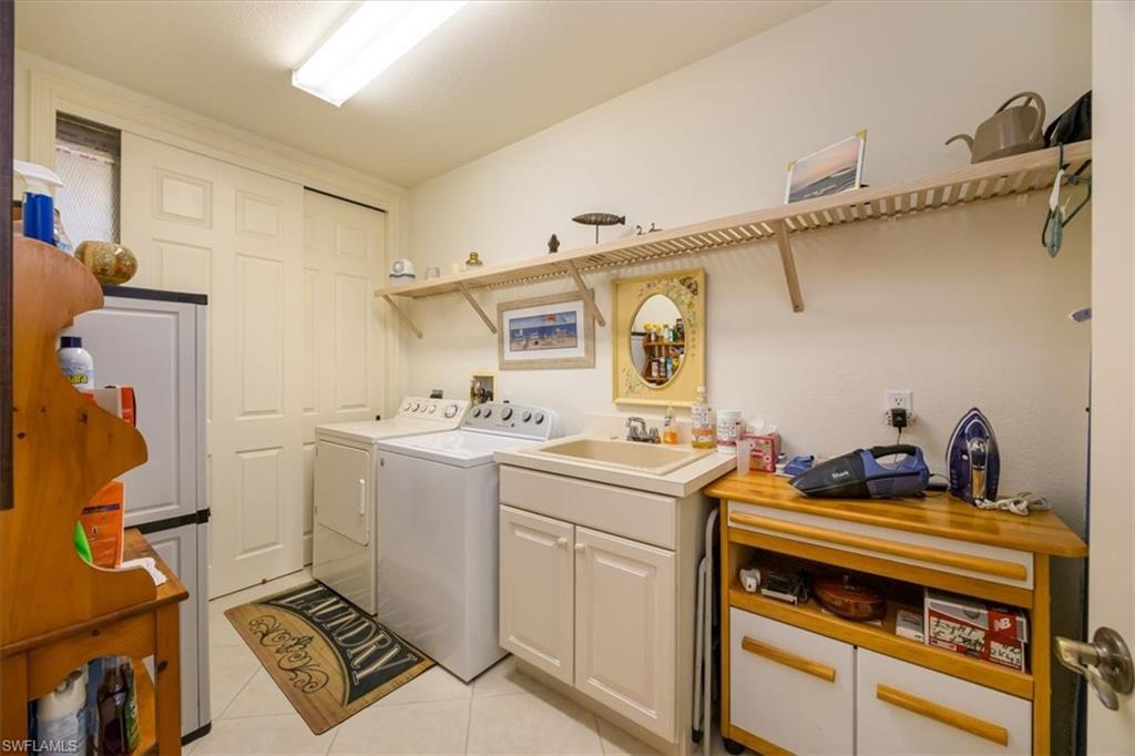 8637 Champions Point, Unit 902 Naples, FL 34113 - Photo 20 of 26 Clothes washing area with light tile patterned flooring, cabinet space, a sink, and washer and dryer