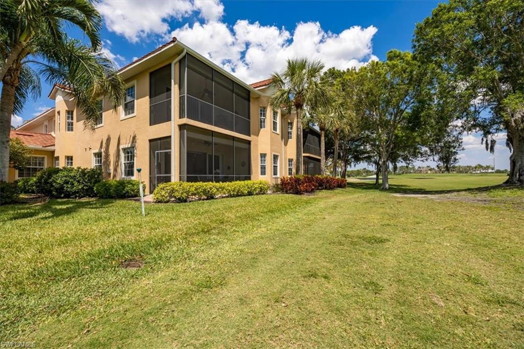 8637 Champions Point, Unit 902 Naples, FL 34113 - Photo 24 of 26 Back of house with stucco siding and a lawn