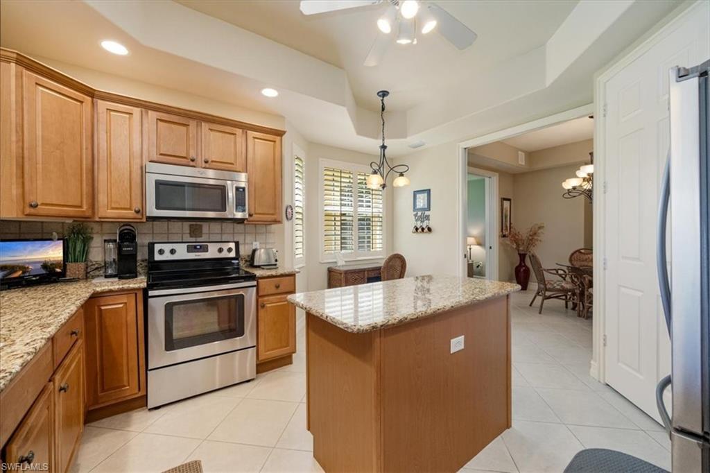 8637 Champions Point, Unit 902 Naples, FL 34113 - Photo 8 of 26 Kitchen with a raised ceiling, appliances with stainless steel finishes, a center island, light tile patterned floors, and decorative backsplash