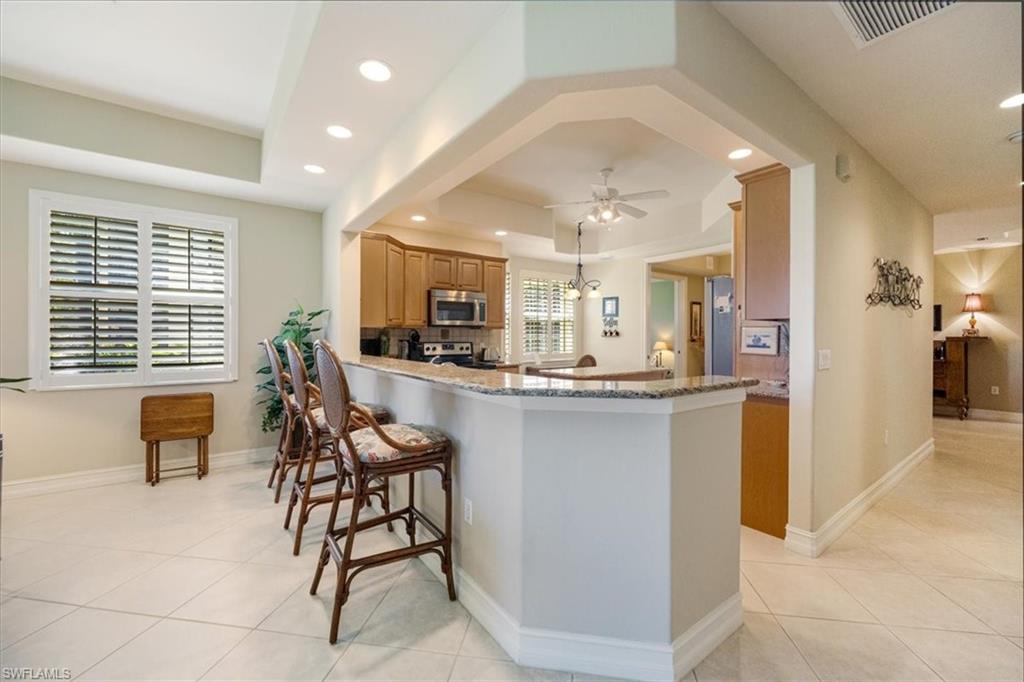 8637 Champions Point, Unit 902 Naples, FL 34113 - Photo 10 of 26 Kitchen with a tray ceiling, light tile patterned floors, stainless steel appliances, ceiling fan, and recessed lighting