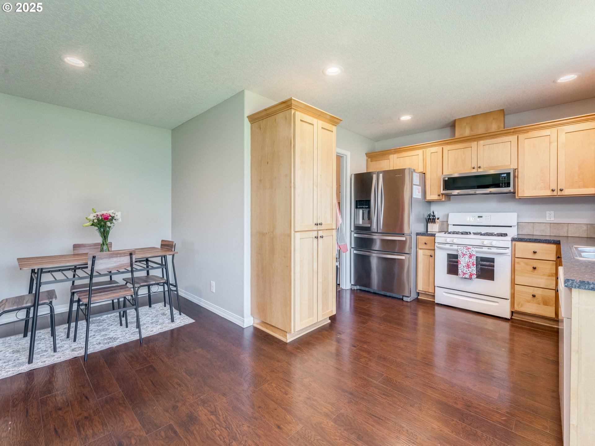 230 Northwest Sagan Loop Sheridan, OR 97378 - Photo 8 of 26 a kitchen with stainless steel appliances a refrigerator a stove top oven a sink dishwasher and a dining table with wooden floor