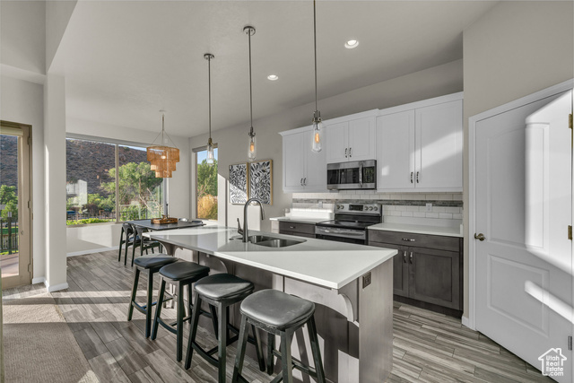 101 Chuckwalla Lane Springdale, UT 84767 - Photo 6 of 51 Kitchen with backsplash, white cabinetry, appliances with stainless steel finishes, hanging light fixtures, and a breakfast bar area