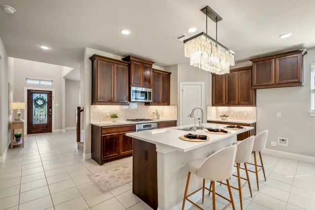 a kitchen with stainless steel appliances granite countertop a stove top oven a sink dishwasher a dining table and chairs with wooden floor