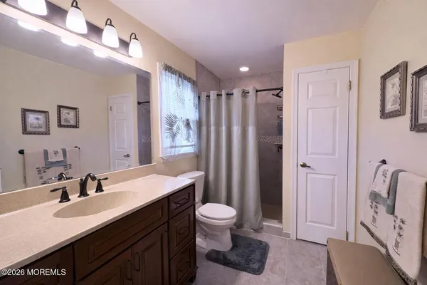 a spacious bathroom with a double vanity sink toilet mirror and shower