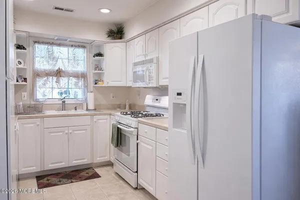 a kitchen with white cabinets and white appliances