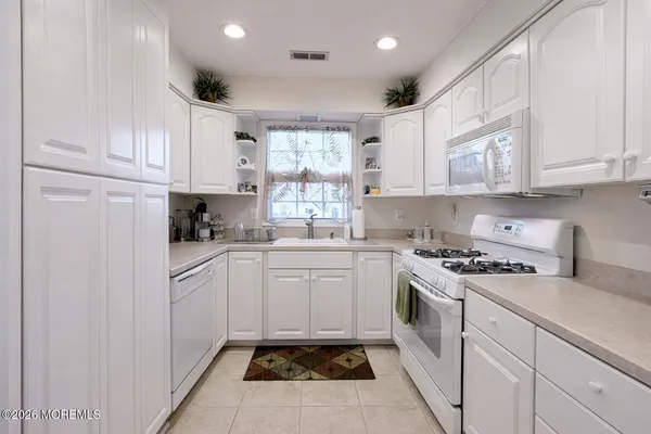 a kitchen with granite countertop white cabinets and white appliances