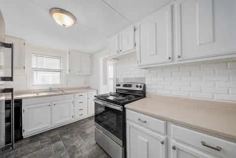 a kitchen with cabinets appliances a sink and a counter top space
