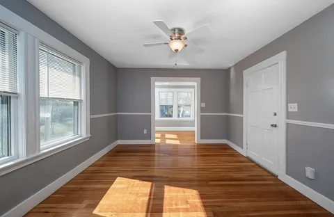 a view of an empty room with wooden floor and a window