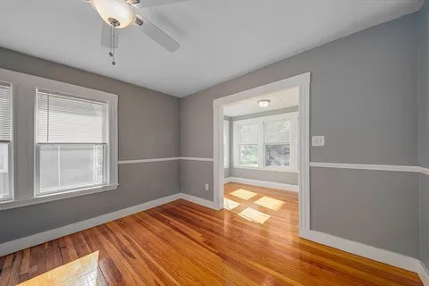 a view of empty room with wooden floor and fan
