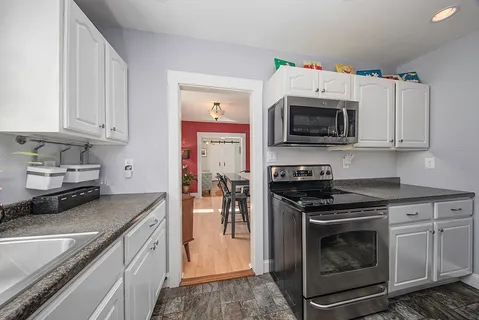 a kitchen with granite countertop a stove top oven microwave and cabinets