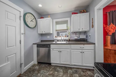 a kitchen with stainless steel appliances granite countertop a sink a stove a clock and a refrigerator