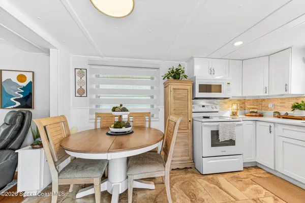 a kitchen with stainless steel appliances granite countertop a dining table chairs and a refrigerator