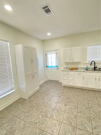 a large white kitchen with a sink and cabinets