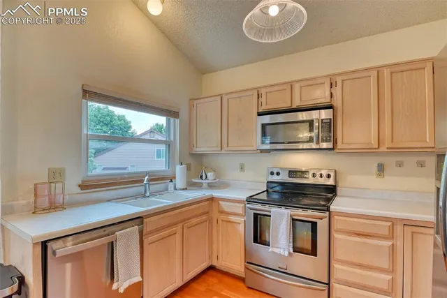 a kitchen with granite countertop a sink cabinets stainless steel appliances and a window