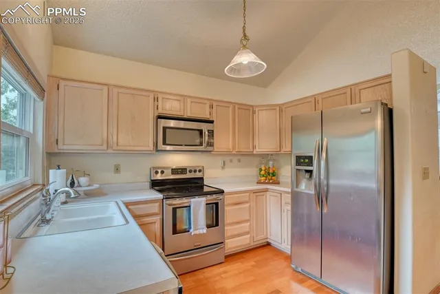 a kitchen with stainless steel appliances granite countertop a refrigerator a sink a stove and white cabinets