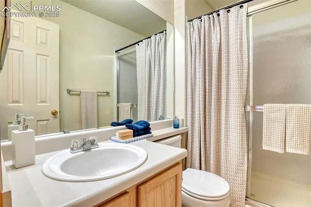 a bathroom with a sink a toilet a mirror and shower