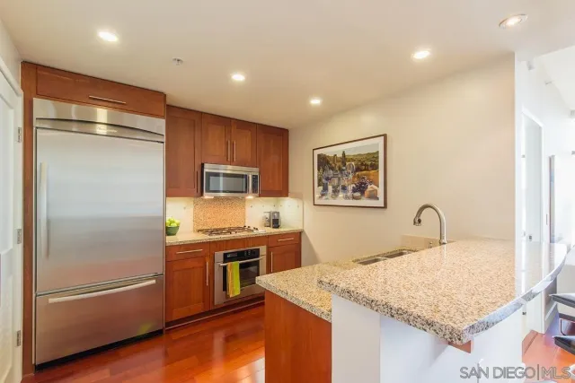 a kitchen with stainless steel appliances granite countertop a refrigerator and a stove top oven