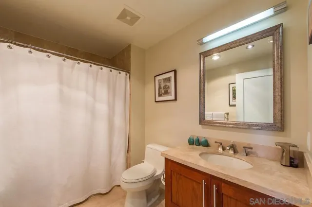 a bathroom with a granite countertop sink mirror vanity and toilet