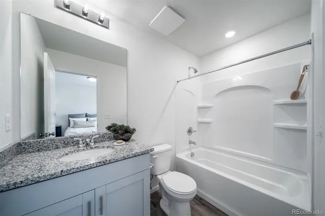 a bathroom with a granite countertop sink a toilet and shower