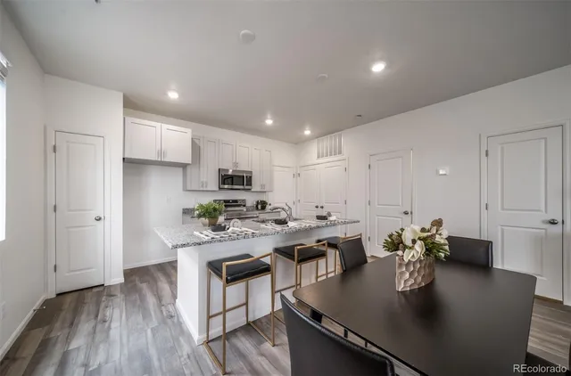 a kitchen with a dining table chairs stove refrigerator and cabinets