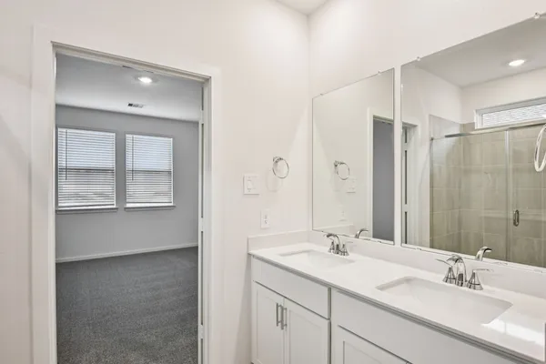 a bathroom with a double vanity sink a large mirror and a bathtub