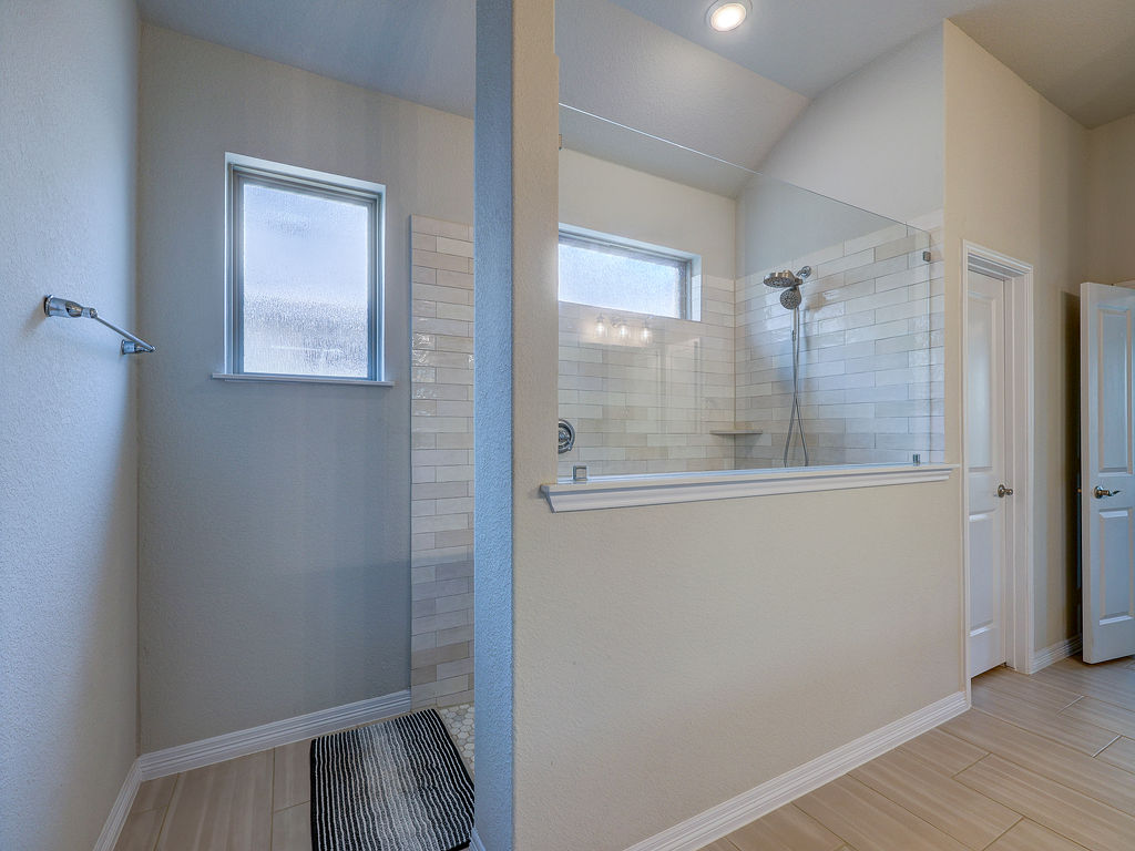 229 Heartleaf Road San Marcos, TX 78666 - Photo 29 of 40 A generously sized shower with subway tile surrounds features a built-in shelf and glass partition.