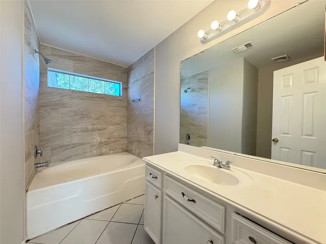 a bathroom with a bathtub shower sink vanity and mirror