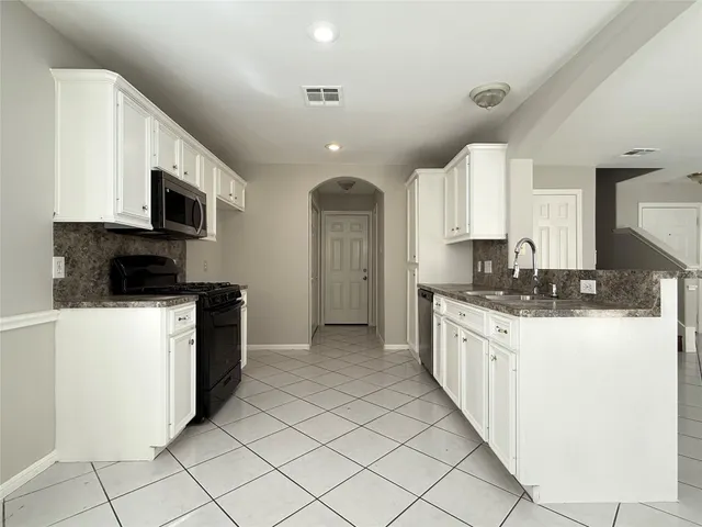 a kitchen with granite countertop a sink a stove top oven and cabinets