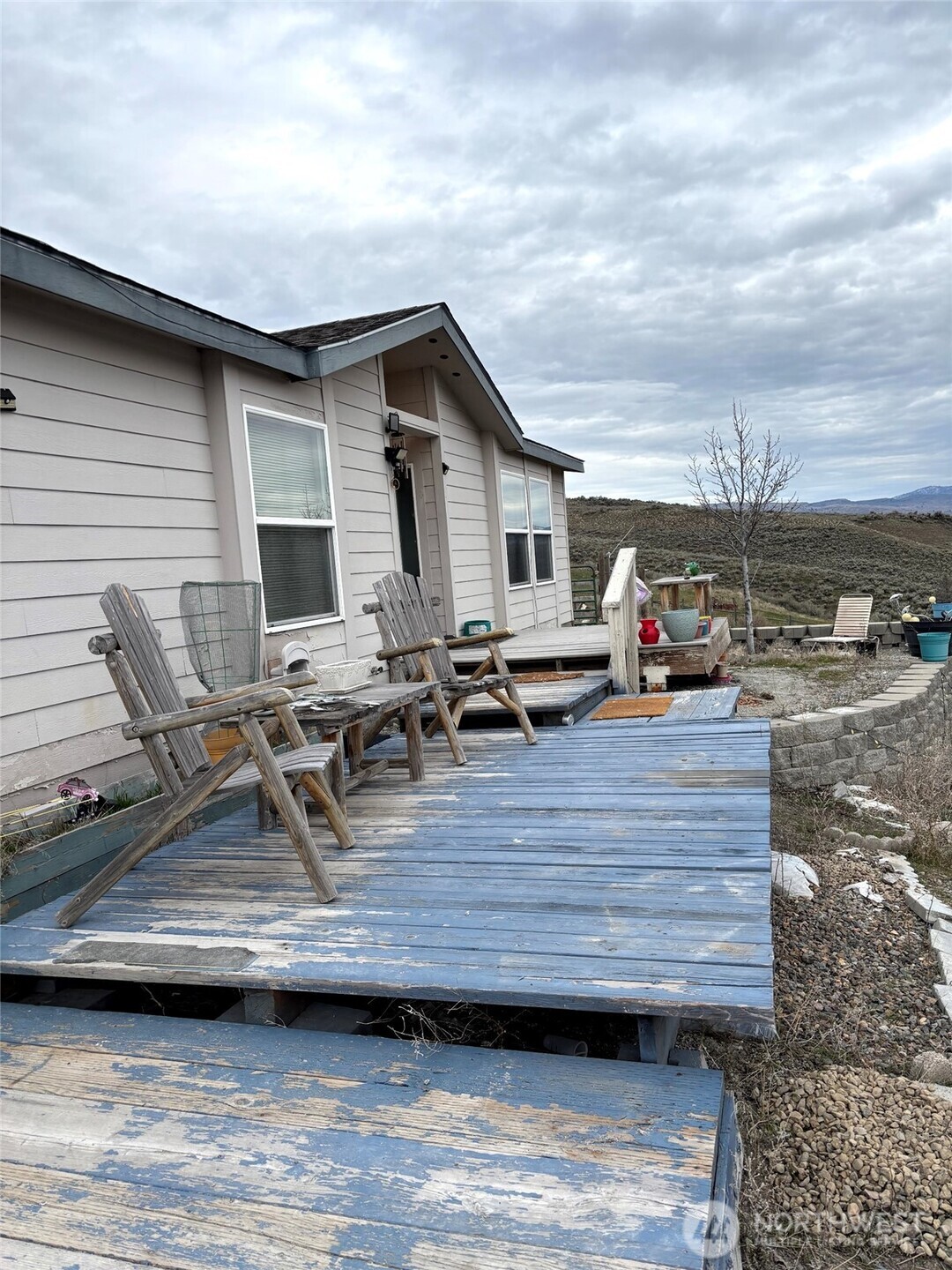 1579 Pine Creek Road, Unit A Tonasket, WA 98855 - Photo 3 of 24 a view of a roof deck with table and chairs a barbeque with wooden floor and fence
