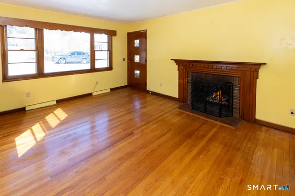 an empty room with wooden floor and a fireplace