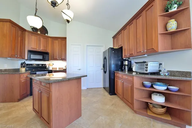 a kitchen with stainless steel appliances granite countertop a refrigerator a stove a sink dishwasher and a microwave with wooden floor