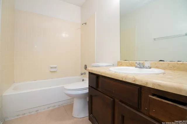 a bathroom with a granite countertop bathtub sink vanity mirror and toilet