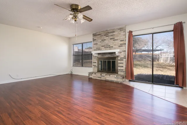a view of empty room with wooden floor and fireplace