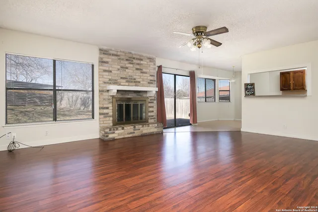 a view of an empty room with a window and wooden floor