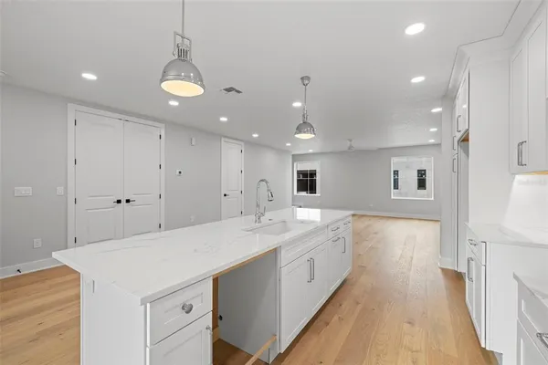 a large white kitchen with a lot of counter space and wooden floor