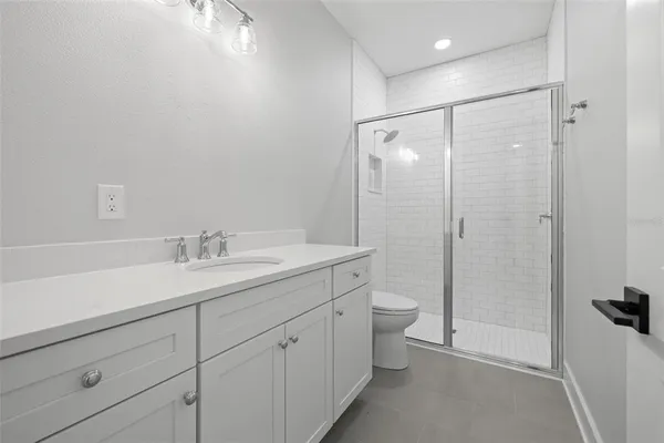 a bathroom with a shower sink vanity mirror and toilet