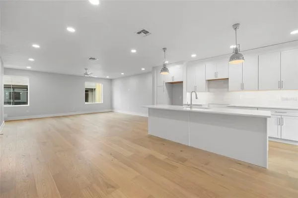 a large white kitchen with kitchen island a sink dishwasher a stove and a refrigerator with wooden floor