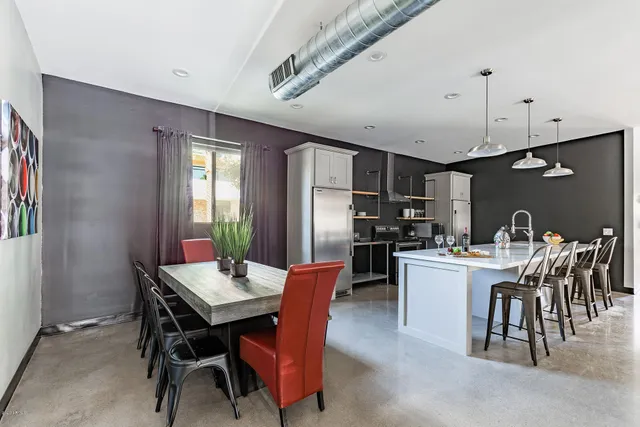 a kitchen with stainless steel appliances granite countertop a dining table chairs and refrigerator