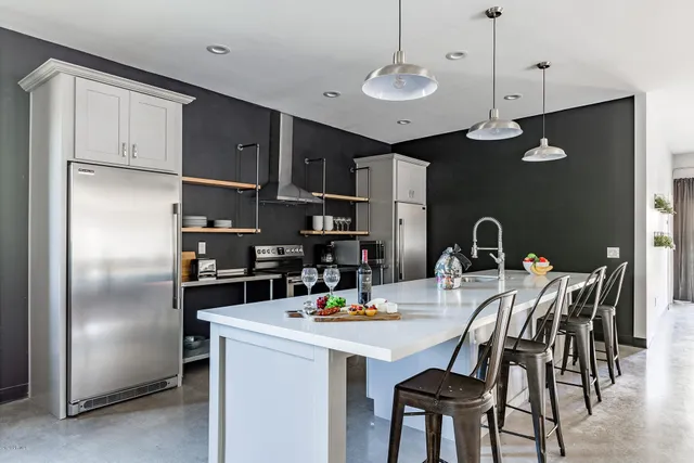 a kitchen with stainless steel appliances granite countertop a dining table chairs refrigerator and cabinets